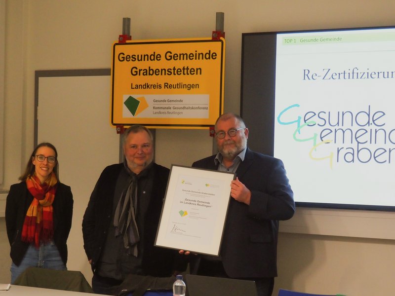 Foto: Übergabe der Re-Zertifizierungsurkunde in der Sitzung des Gemeinderats Grabenstetten am 18.02.2025. Sophia Keßler, Frank Havlicek (Landratsamt Reutlingen, Abteilung Gesundheitsplanung) und Bürgermeister Roland Deh (v.l.n.r.).