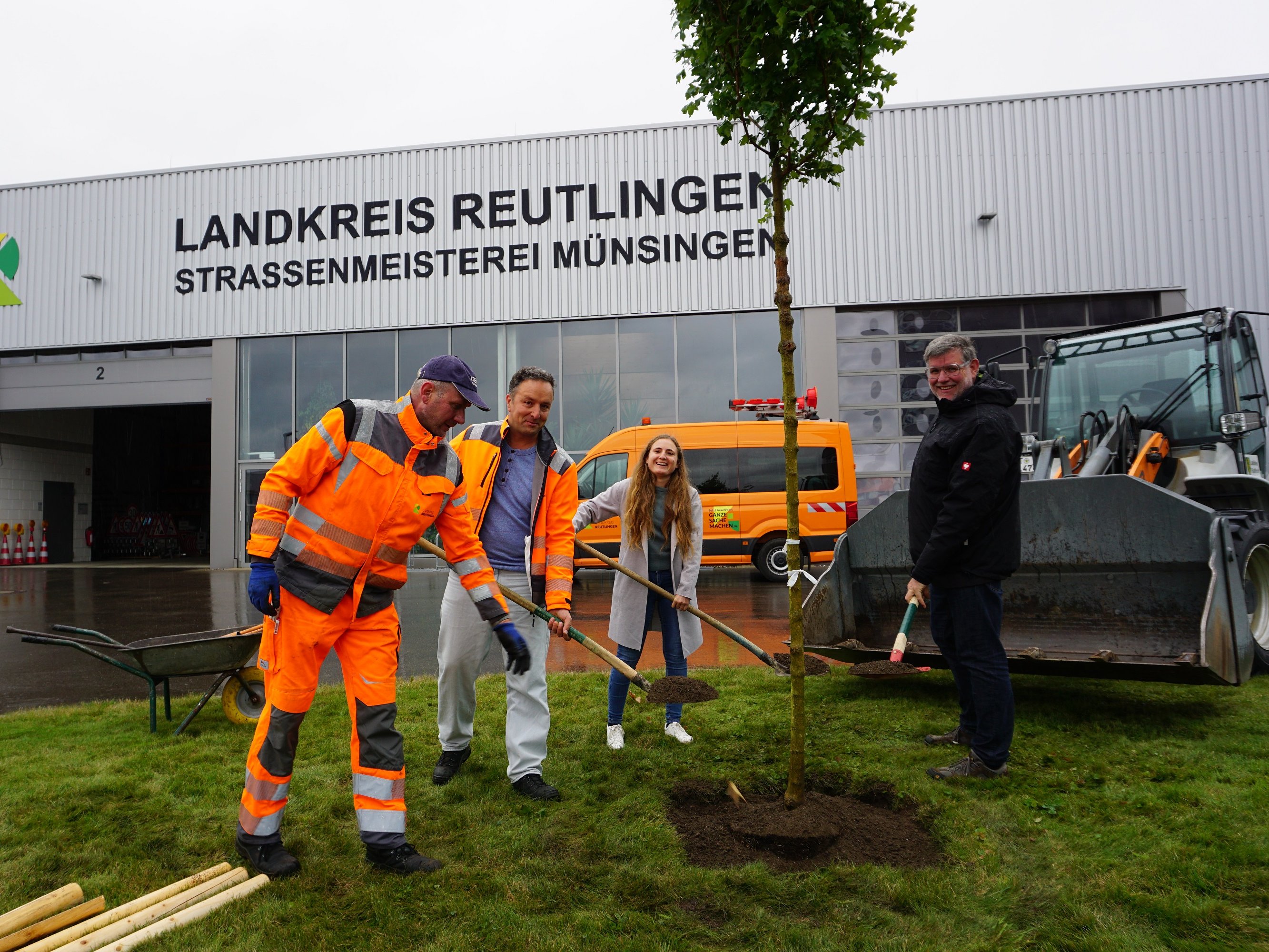 Landrat Dr. Ulrich Fiedler (r.) setzte gemeinsam mit Hannah Czichowsky (Klimaschutzbeauftragte Landratsamt Reutlingen, m.) und den beiden Kollegen Bernd Geiselhart (Hofverwalter, l.) und Daniel Horn (Stellvertretung Straßenmeisterei Münsingen, 2.v.l.) der Straßenmeisterei Münsingen einen neuen Baum ein. 